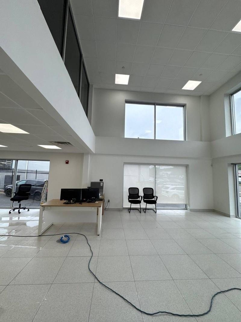 Large empty commercial showroom with tall windows and a tiled floor during cleaning